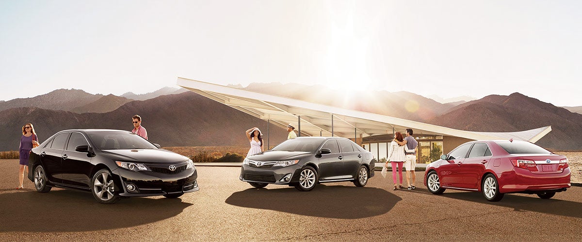 image of people standing next to Toyota sedans with a mountain scene in the background