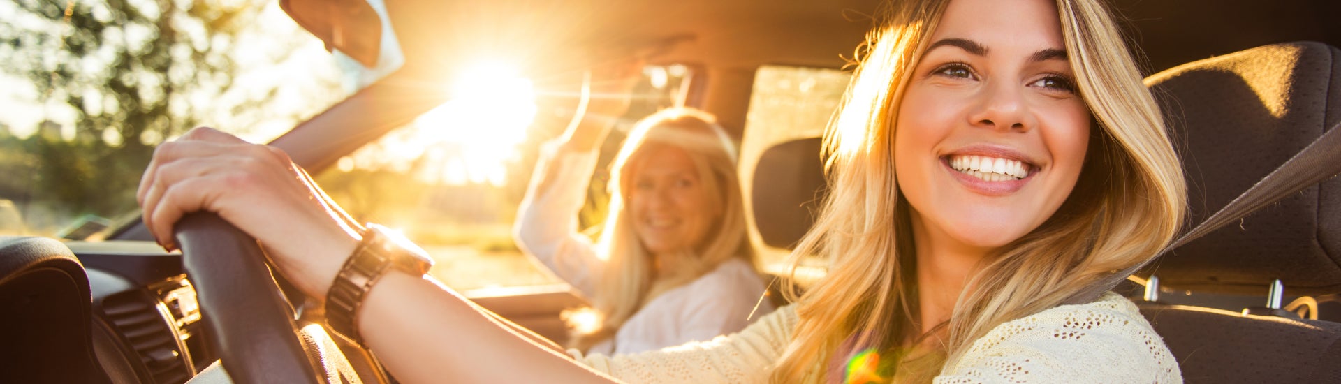 Mother and daughter driving off the lot with their new vehicle