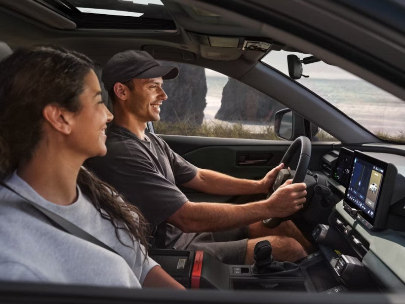 A man and woman are seated in a 2026 Toyota RAV4, focused on the road while driving.